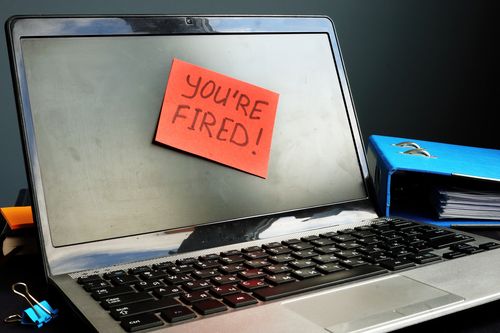 Image is of a posted note on a laptop that says "you're fired!" concept of 5 questions about wrongful termination