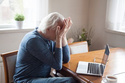 Stressed older man with laptop, Studio City age discrimination lawyers concept