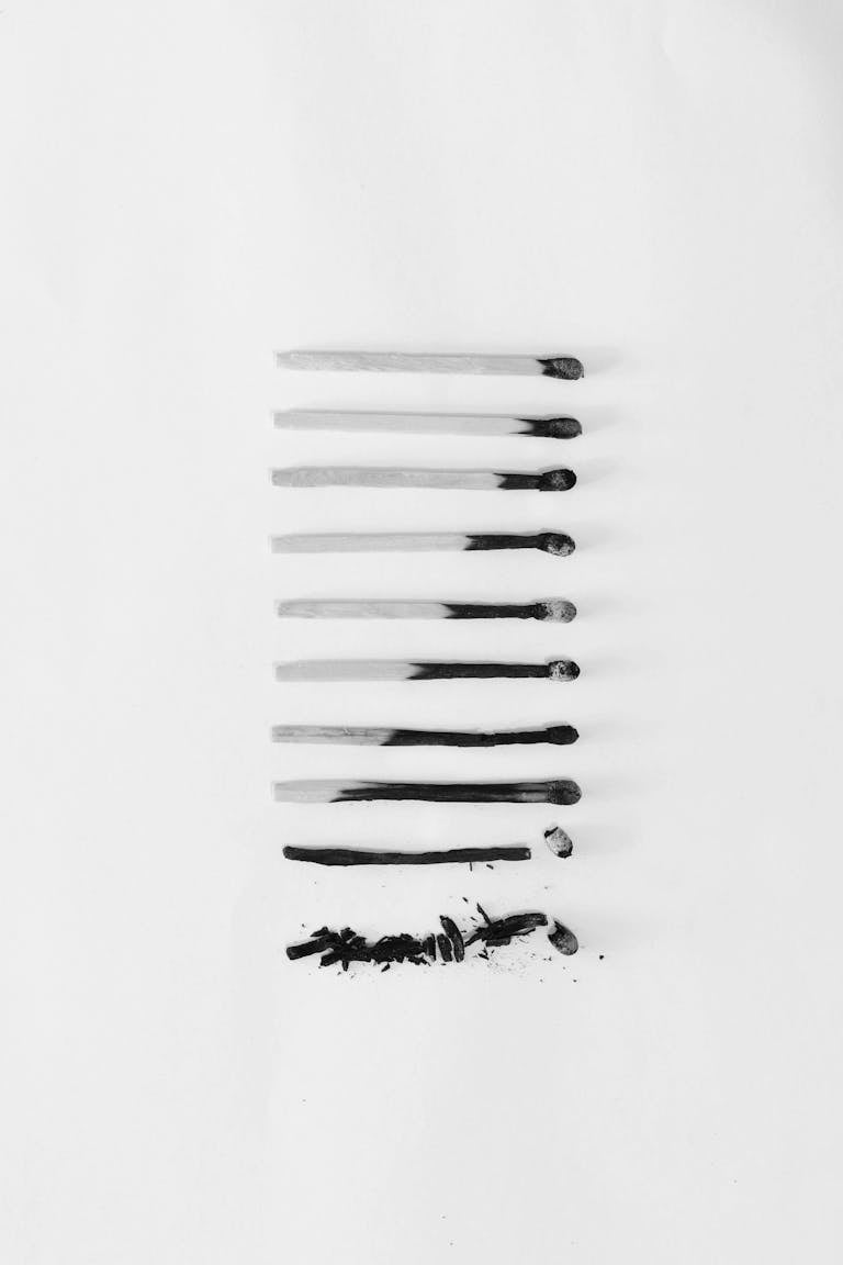 Artistic black and white image of burned matches arranged on a white background, symbolizing burnout.