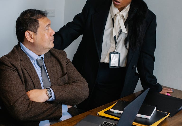 Serious colleagues wearing formal clothes gathering at table and having discussion while working together in contemporary office