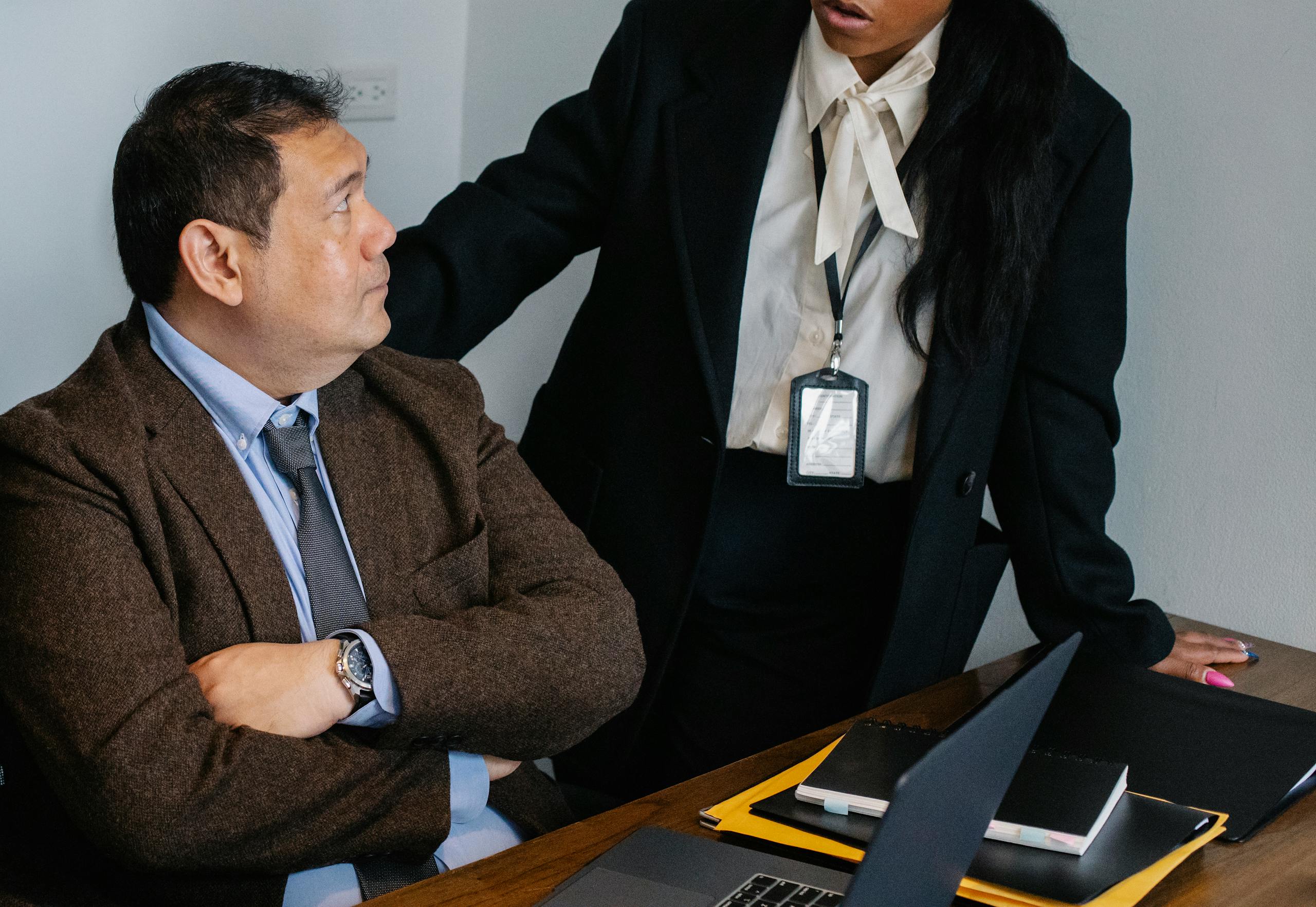 Serious colleagues wearing formal clothes gathering at table and having discussion while working together in contemporary office